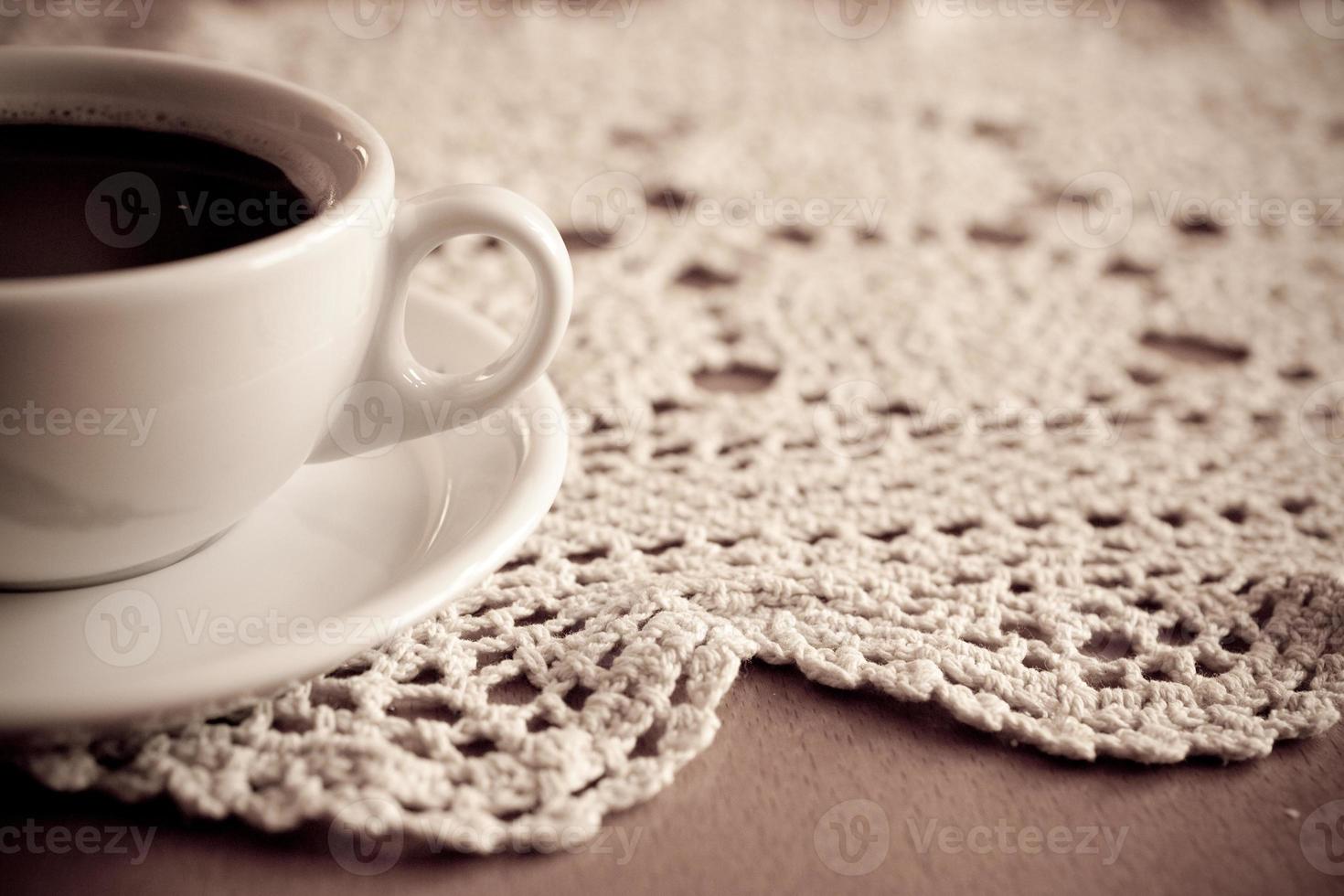 white cup with black coffee on a hand-made tablecloth photo