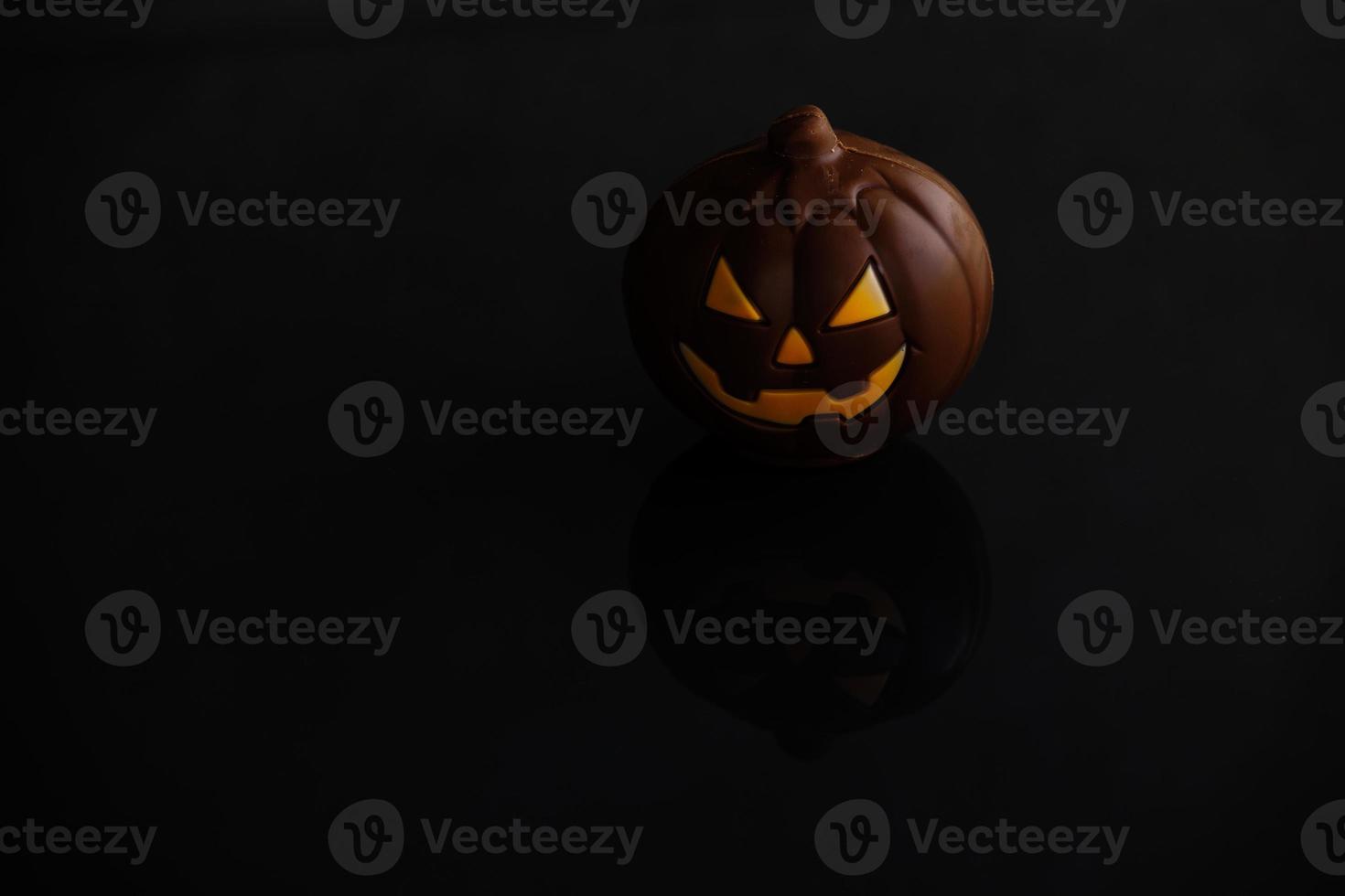 chocolate halloween pumpkin jack-o-lantern on dark background photo