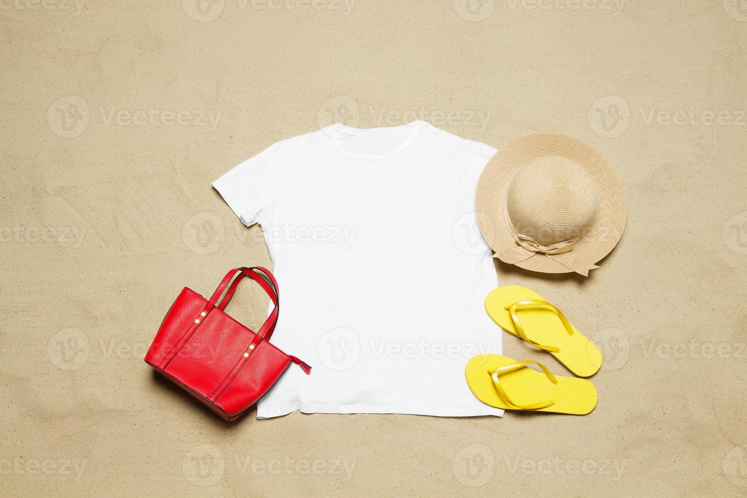 Sand beach texture background. Mockup white summer t-shirt copy space. Blank template woman shirt Top view. Summertime accessories hat, flip-flops, bag. Flat-lay closeup tshirt on seashore. Beachtime photo