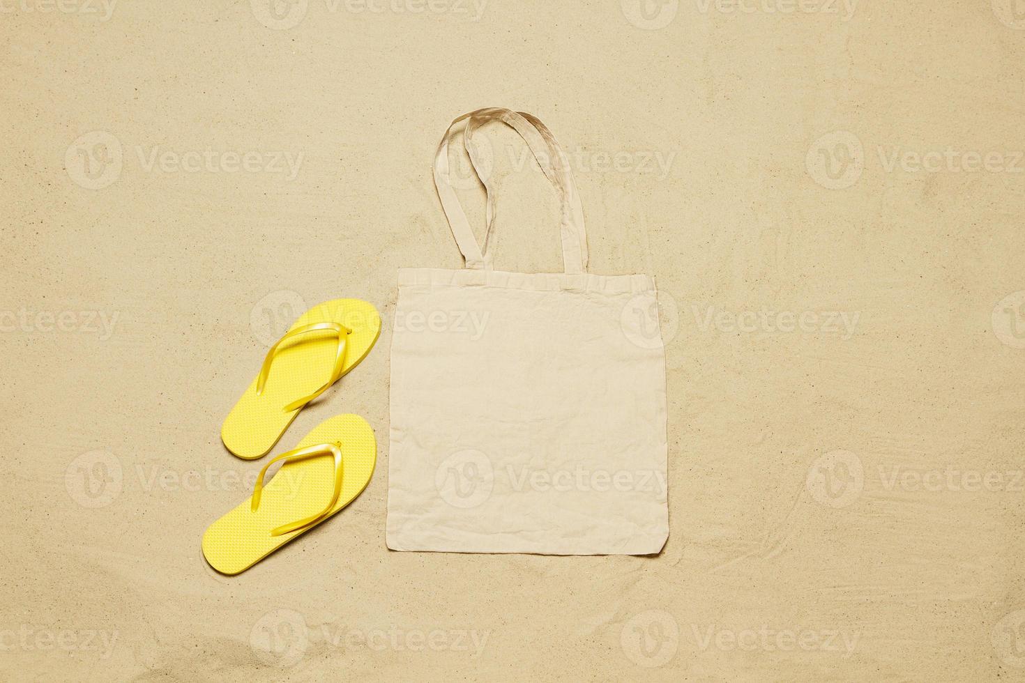 Mockup shopper handbag beach sand background. Top view copy space shopping eco reusable bag. Flip flops accessories. Template blank top view white cotton material canvas cloth. Empty mock-up beach photo