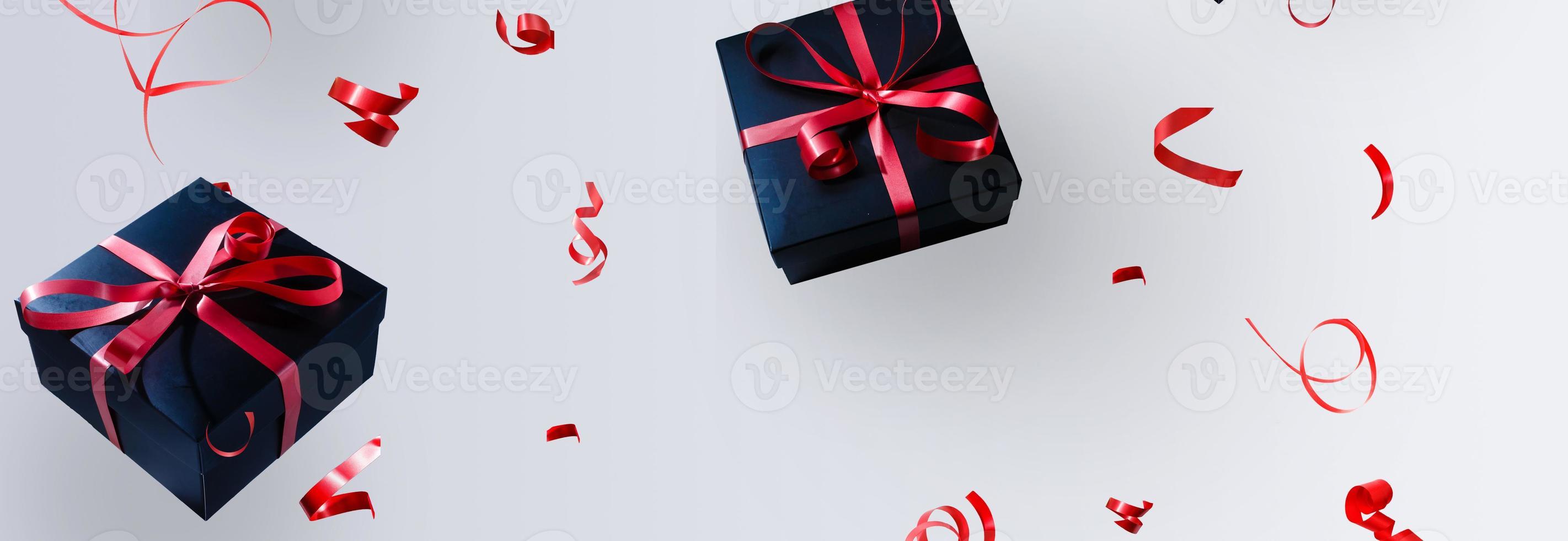 Black gift box with red satin ribbon and bow, over white background. photo