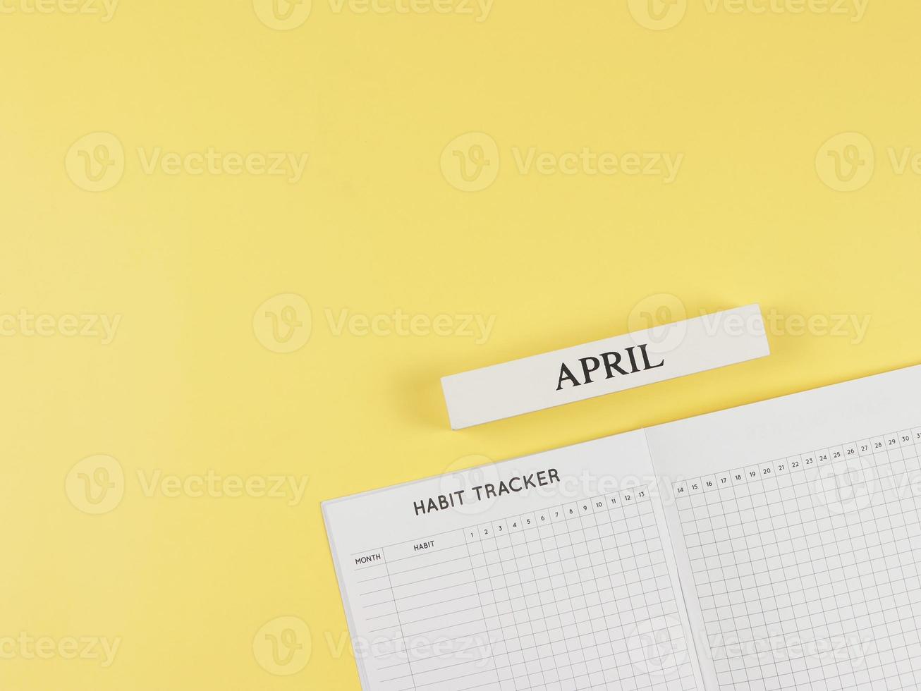 flat layout of Habit tracker book, wooden calendar April  on yellow background with copy space. photo