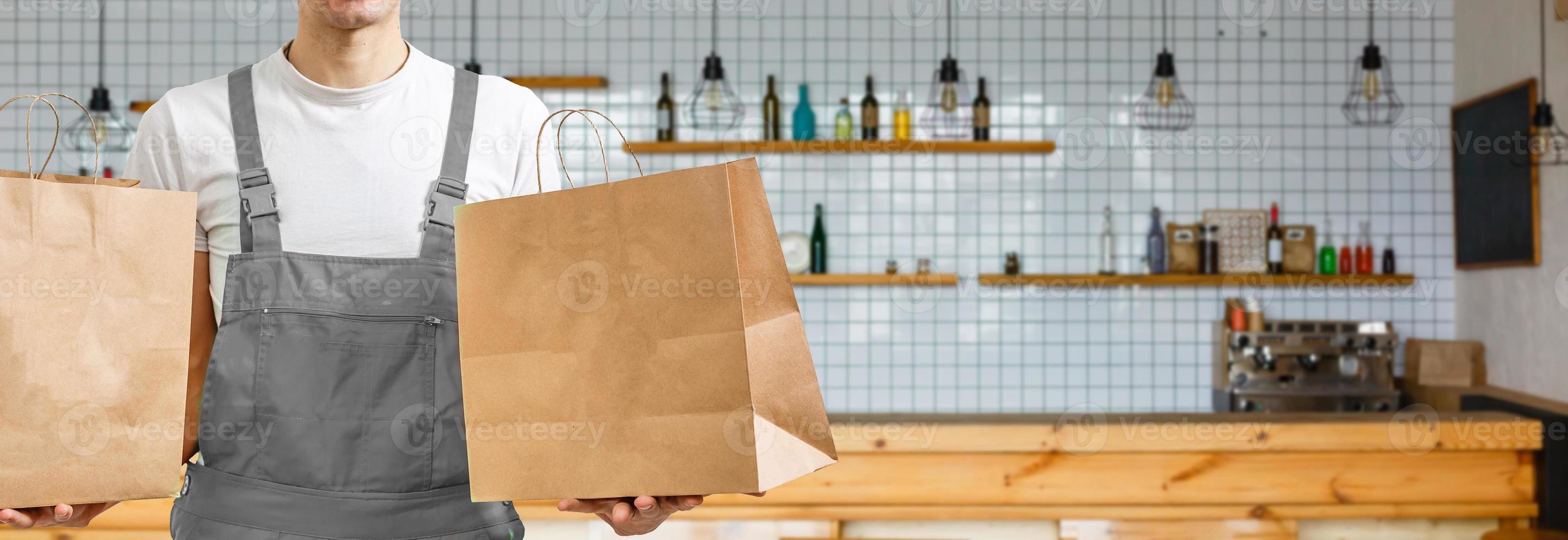 delivery, mail and people concept - happy man delivering food in disposable paper bag to customer home photo