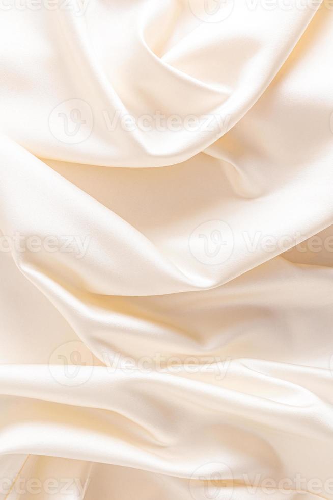 Delicate waves of satin fabric of beige color. vertical view. wedding background. photo