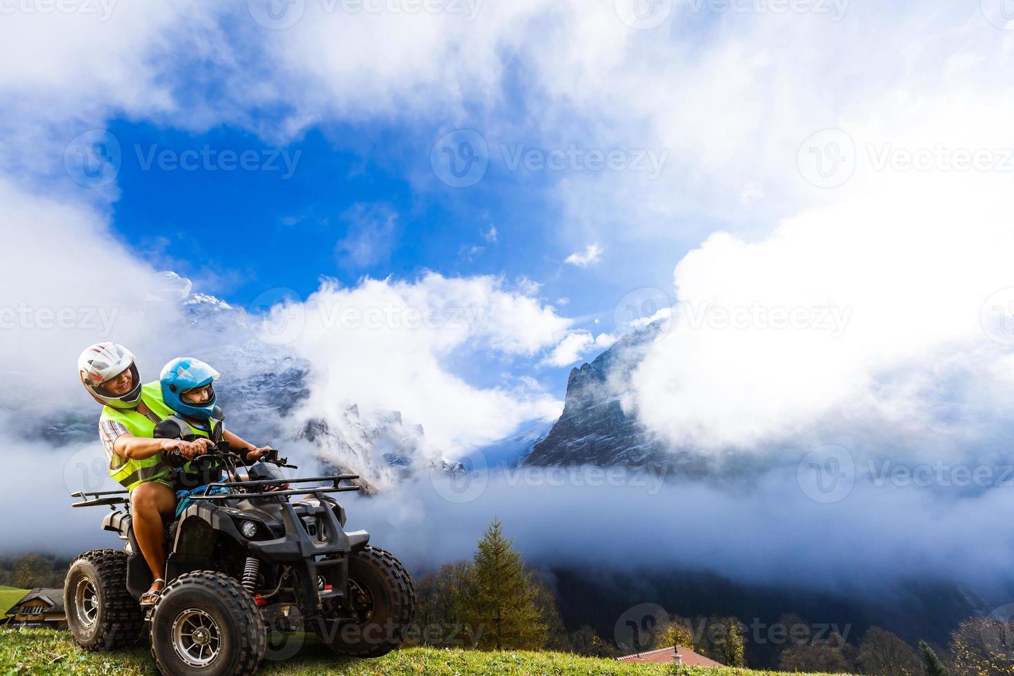 Happy family riding and looking quad bike on mountain. Cute boy on quadricycle. Family summer vacation activity. photo
