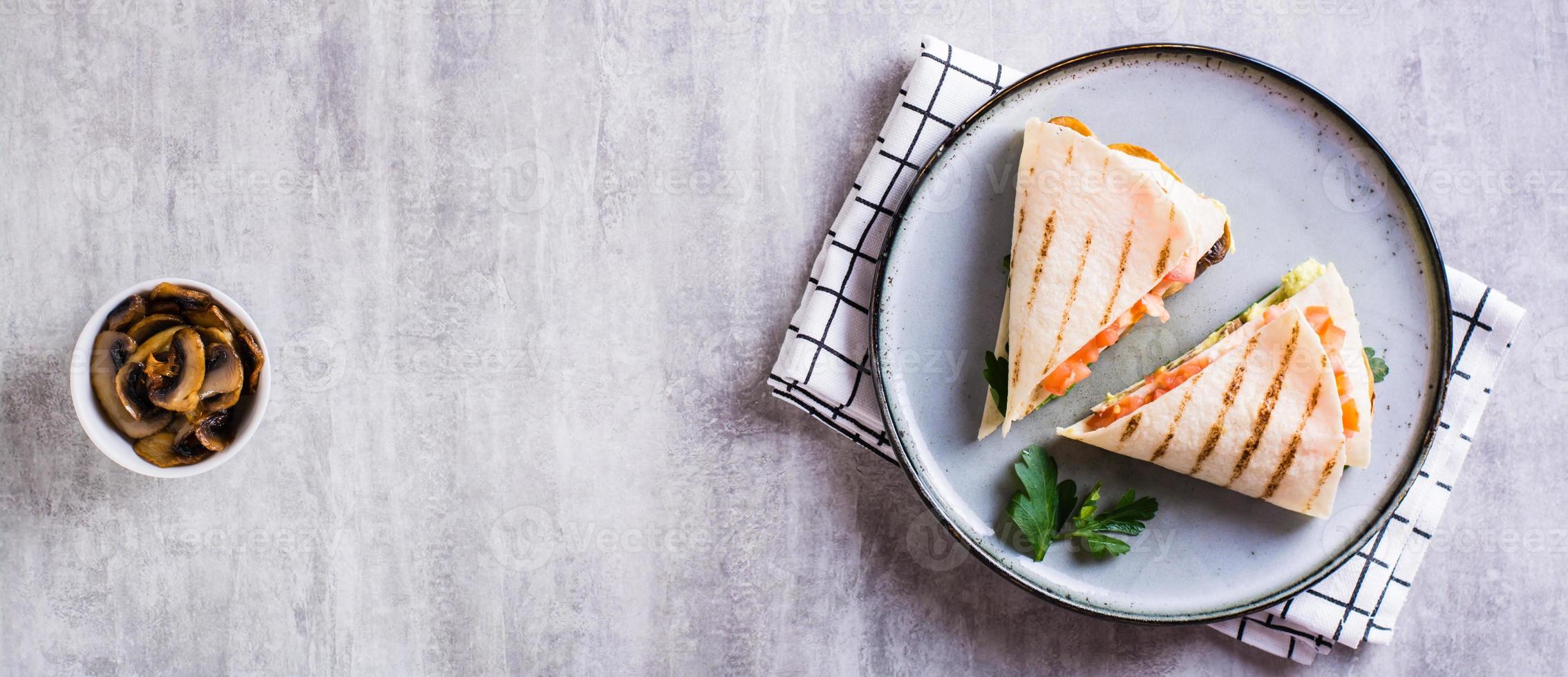Grilled flatbread stuffed with avocado, mushrooms, tomatoes and parsley top view web banner photo