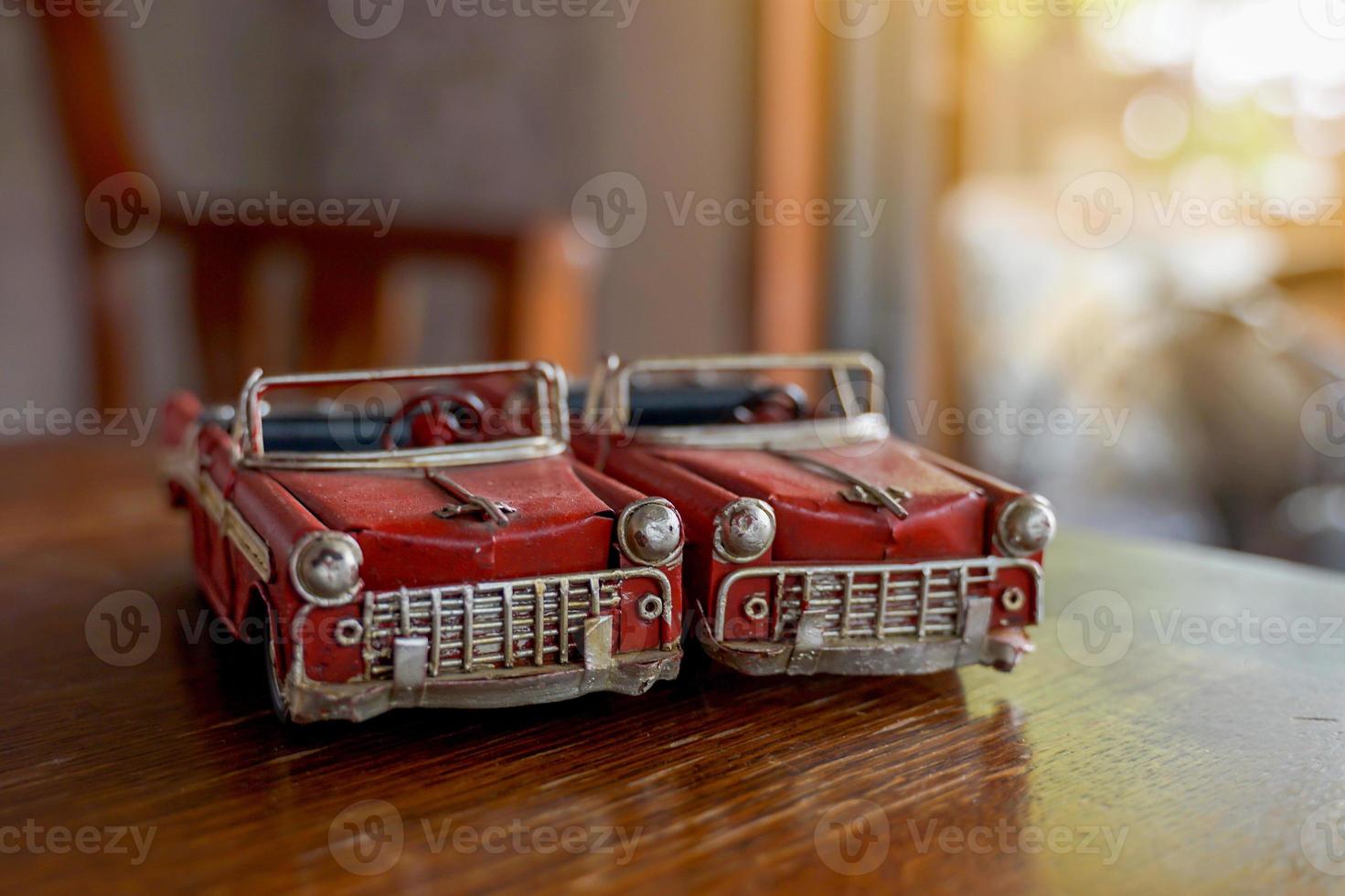 2 old red convertible car models placed side by side on a wooden table. Concept, collectibles, toys, decorations. Soft and selective focus. photo