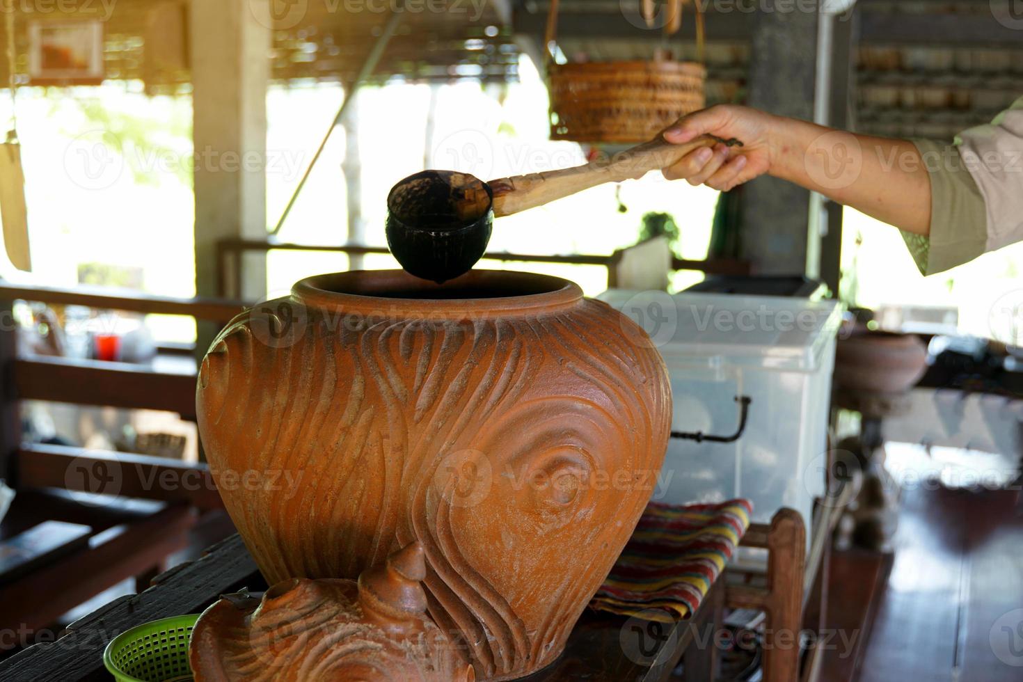 Use a dipper to draw water from a clay pot, which was the home drinking water point of villagers in the north or northeast of Thailand in the past. Soft and selective focus. photo