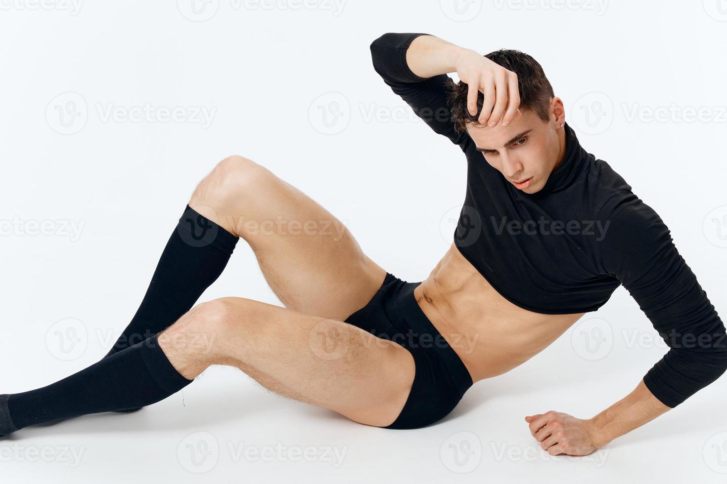a guy in a sweater shorts and socks lies on the floor on a light background in full growth model photo