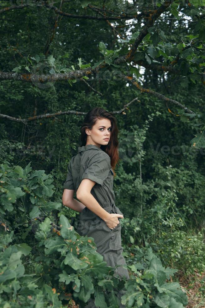 Woman in the forest green leaves hands in pockets fresh air background photo