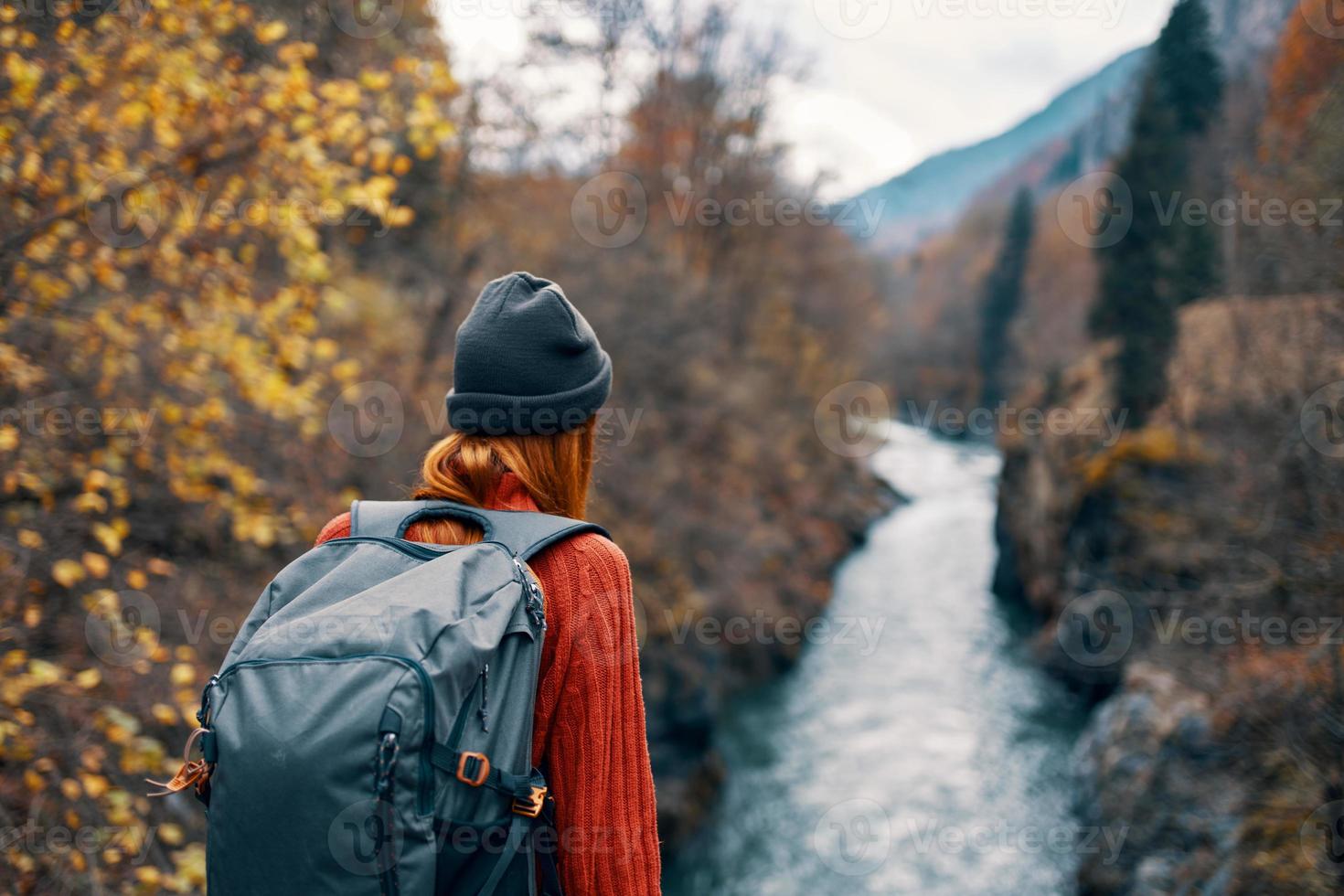 woman hiker with a backpack on her back near a mountain river in nature, back view photo