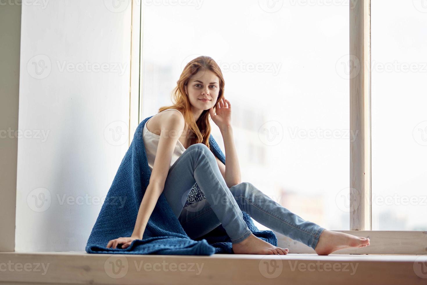 bonito mujer sentado en el antepecho con un azul tartán sonrisa foto