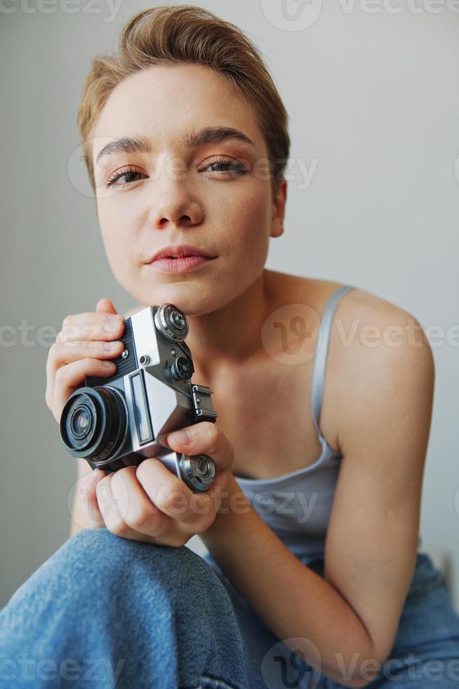 mujer fotógrafo disparo en estudio en antiguo película cámara a hogar en sofá retrato, blanco fondo, gratis Copiar espacio, Lanza libre fotógrafo foto