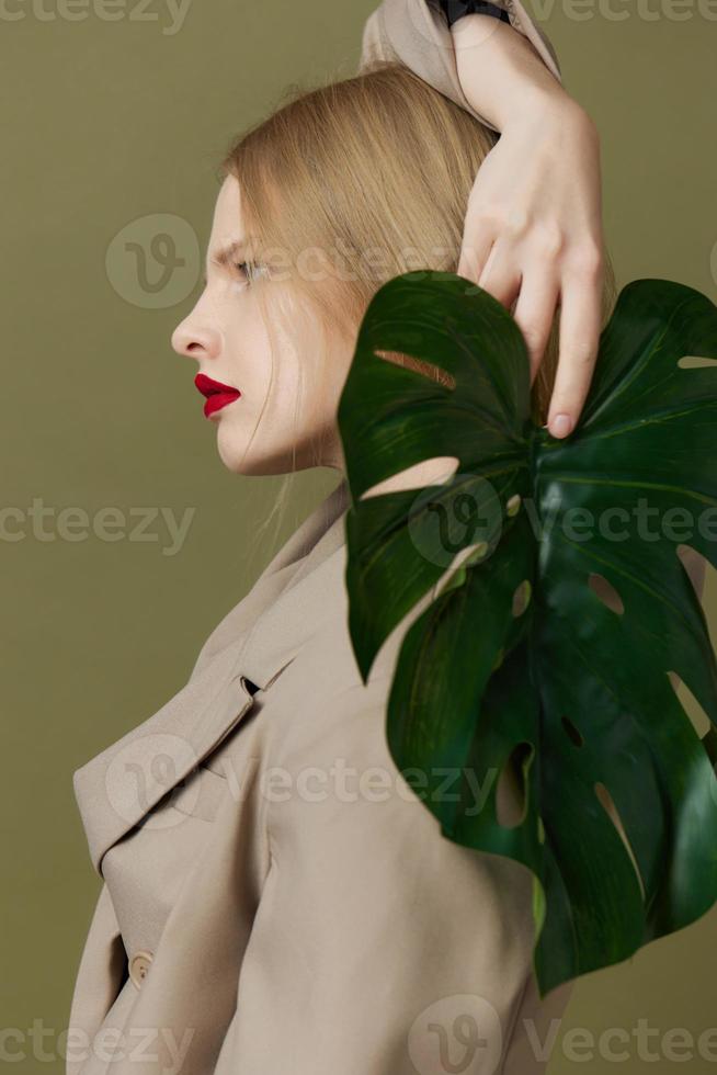 portrait of a woman in coat red lips fashion palm leaf green background photo