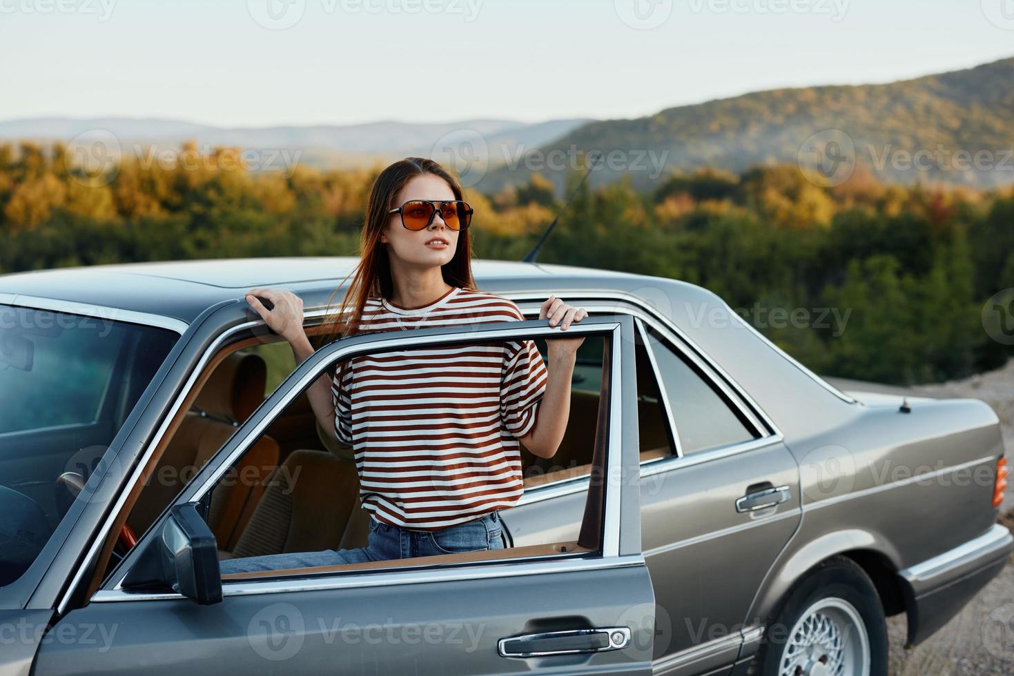 A young woman driver looks out of the car at the autumn landscape and smiles satisfactorily photo