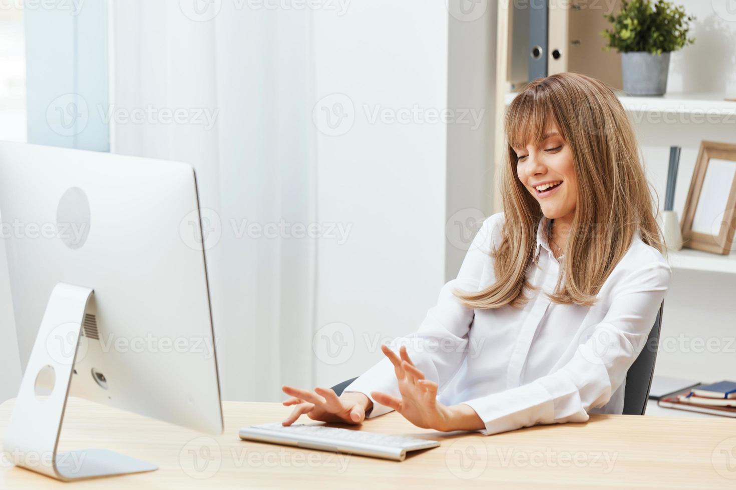 Happy smiling adorable blonde businesswoman typing answer for client look aside sitting at workplace in light modern office. Cheerful employee work on computer online in support service. Copy space photo
