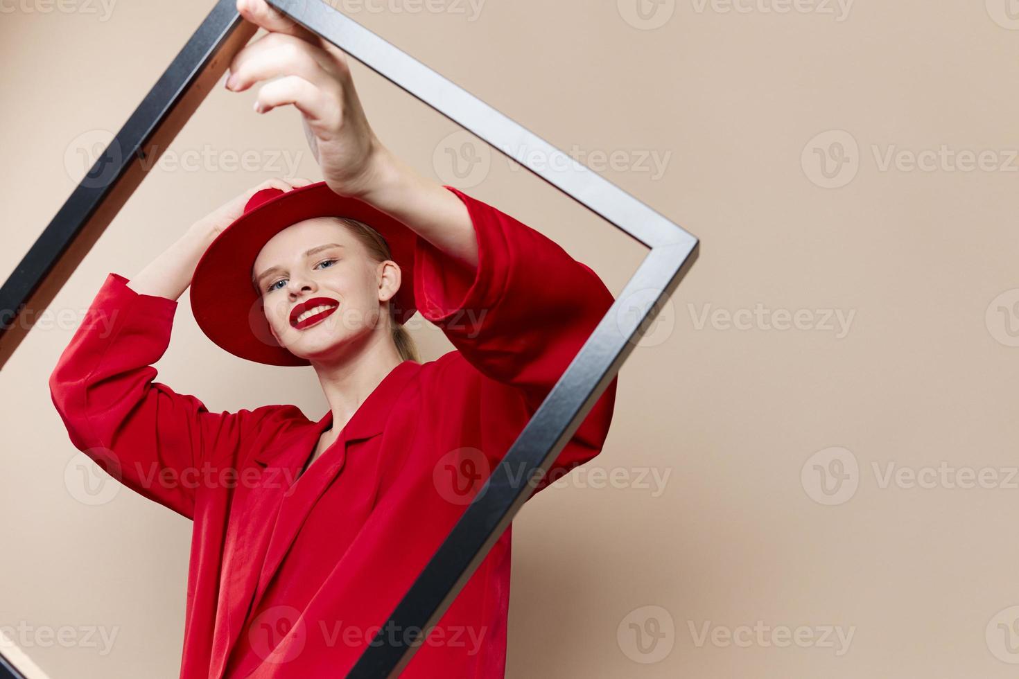 fashionable woman with wooden frame posing red suit beige background photo