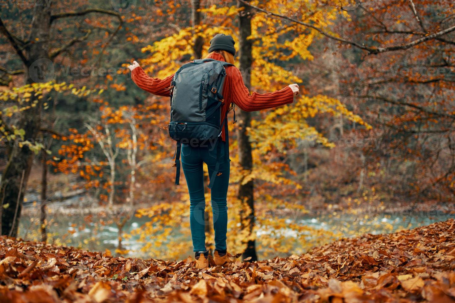 woman in a sweater and jeans and boots in autumn in a park in nature near the river photo