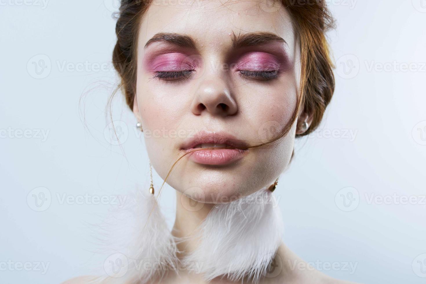woman with bright makeup fluffy earrings bare shoulders close-up photo