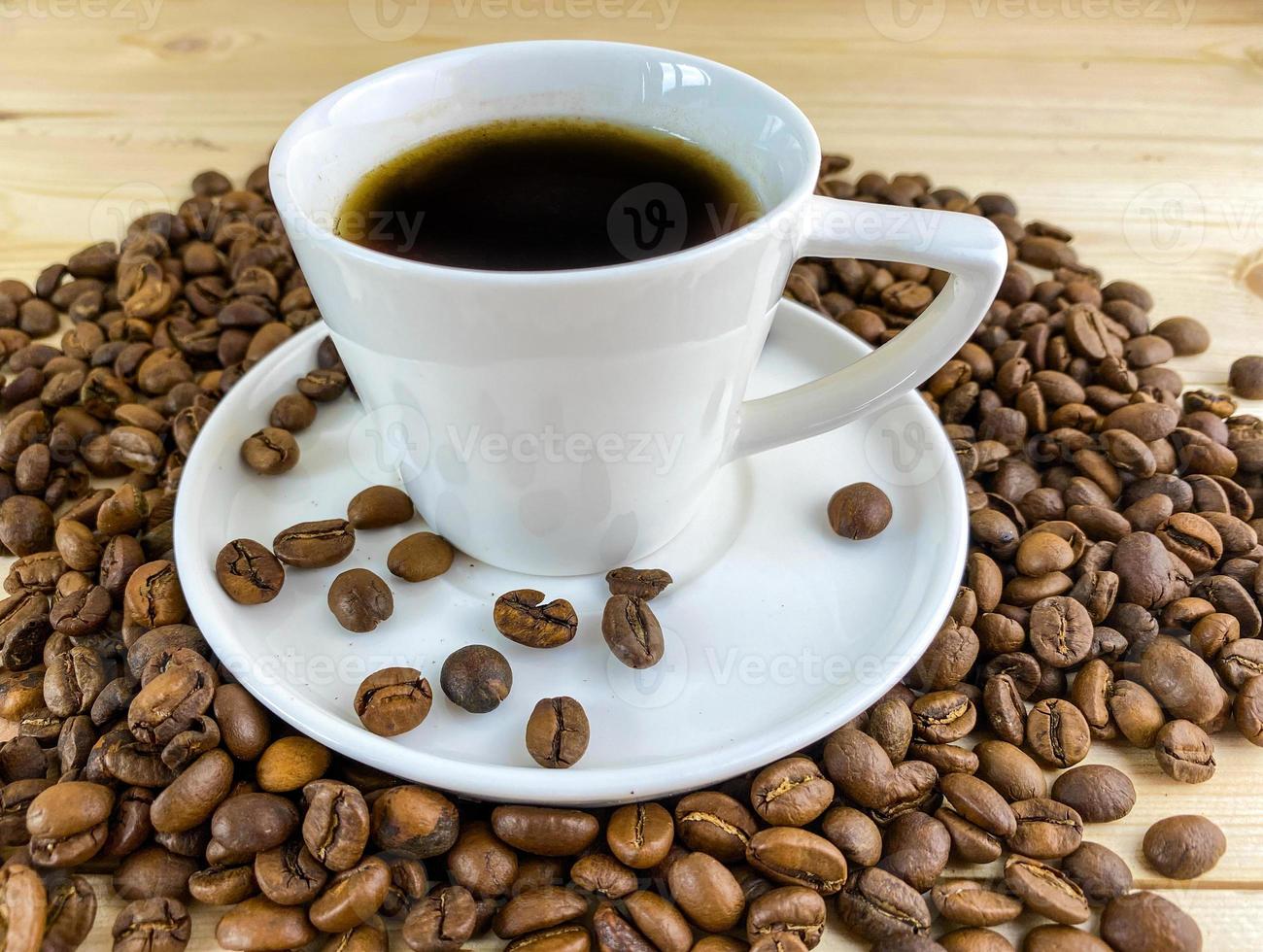 Coffee in a cup with a saucer and coffee grains on a wooden table. photo