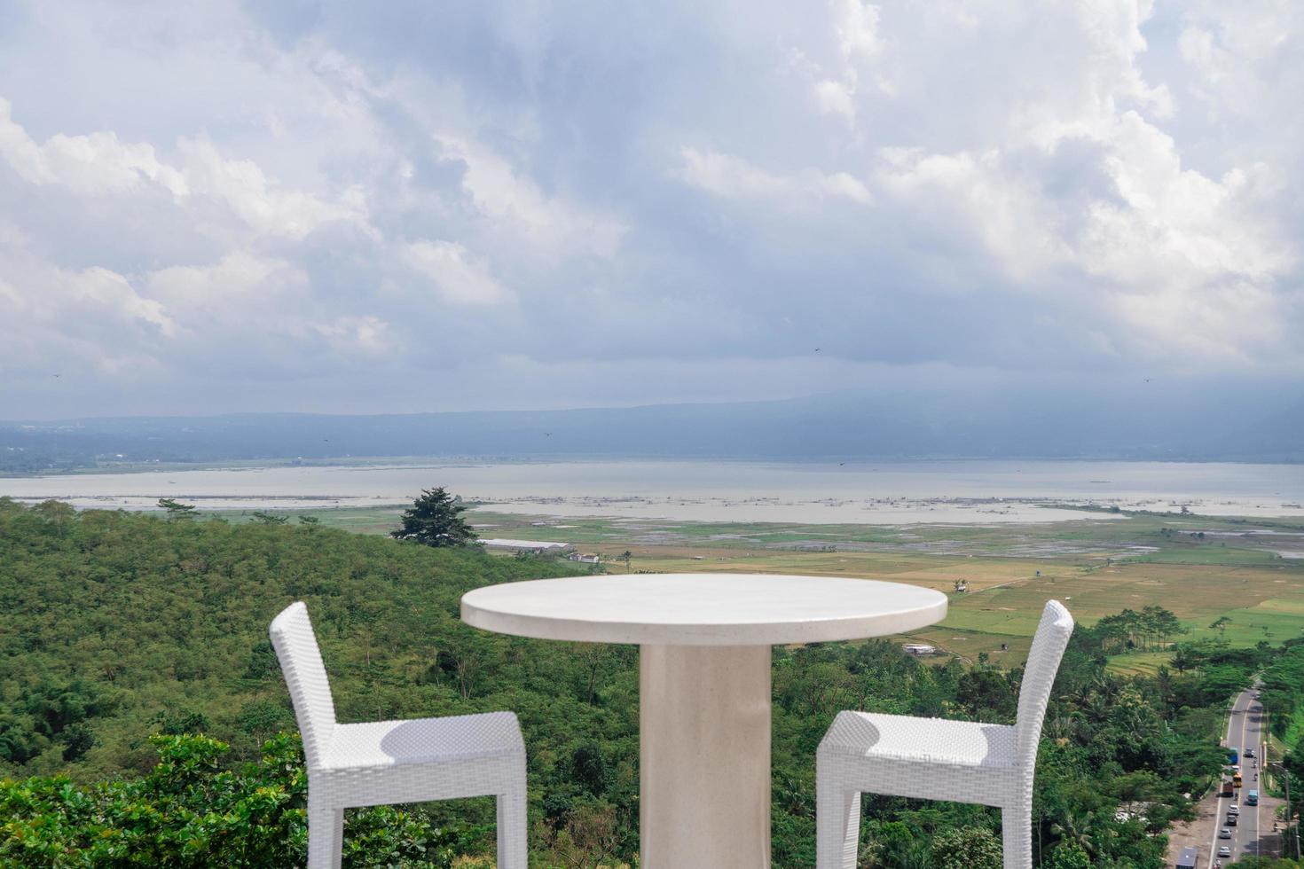 Empty white chair and table with beautiful background and cloudy sky. The photo is suitable to use for traditional food background, poster and food content media.