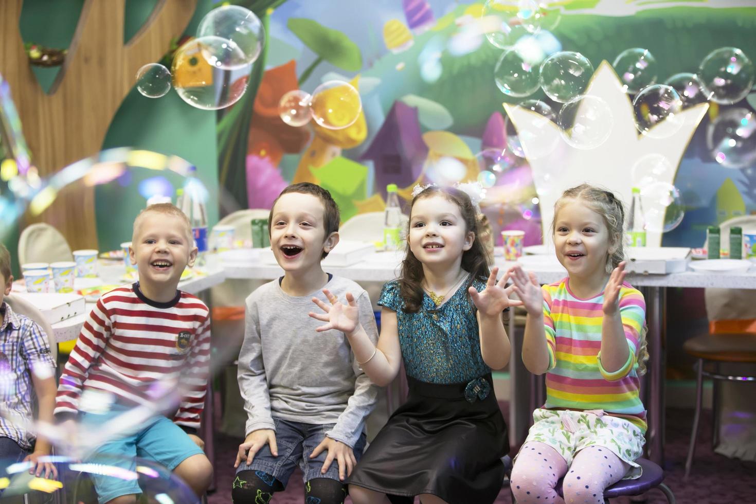 Children at the feast. Soap bubbles show. Children's party. To burst the soap bub photo