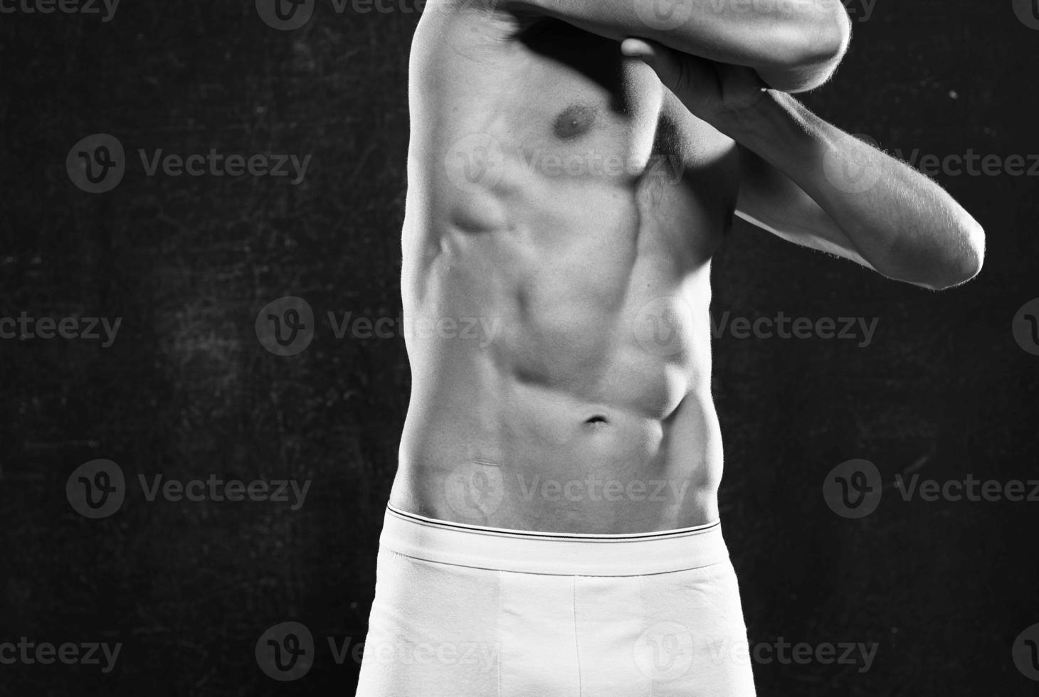 sporty man with a pumped-up body dark background photo