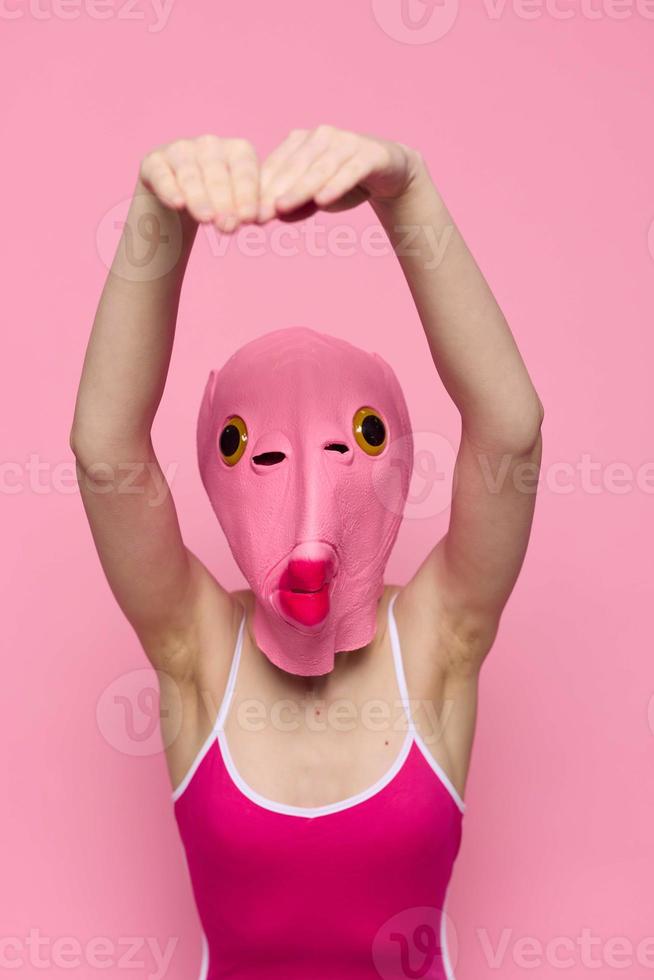 Crazy woman in pink fish head costume poses on pink studio background, provocative Halloween costume photo