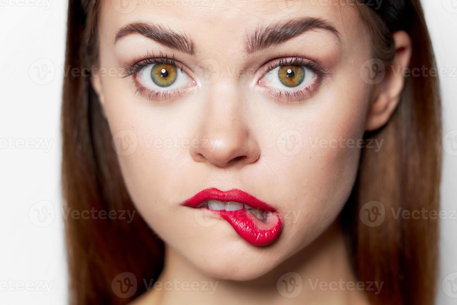 Beautiful woman face close-up red bites her lip photo