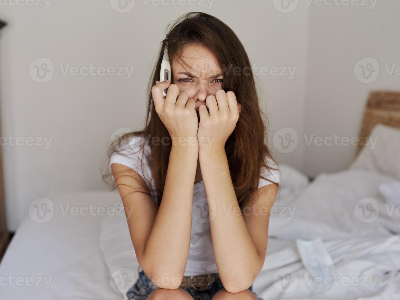 woman with a thermometer in her hands sitting on the bed emotion disorder photo