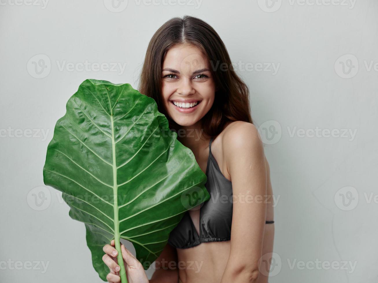 alegre mujer en traje de baño verde palma hoja aislado antecedentes sonrisa foto