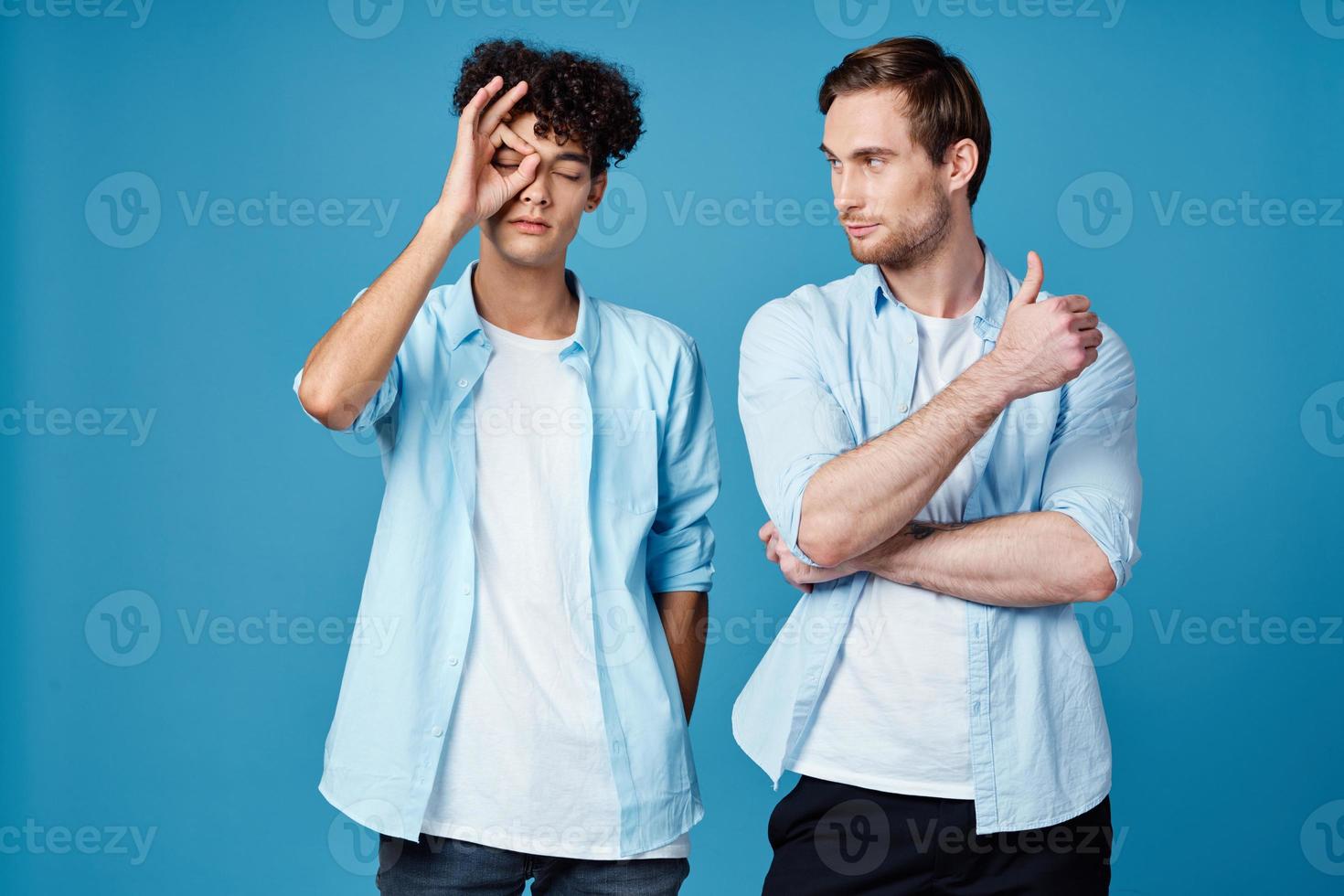 joven hombres en idéntico camisetas y azul camisas chateando amigos foto