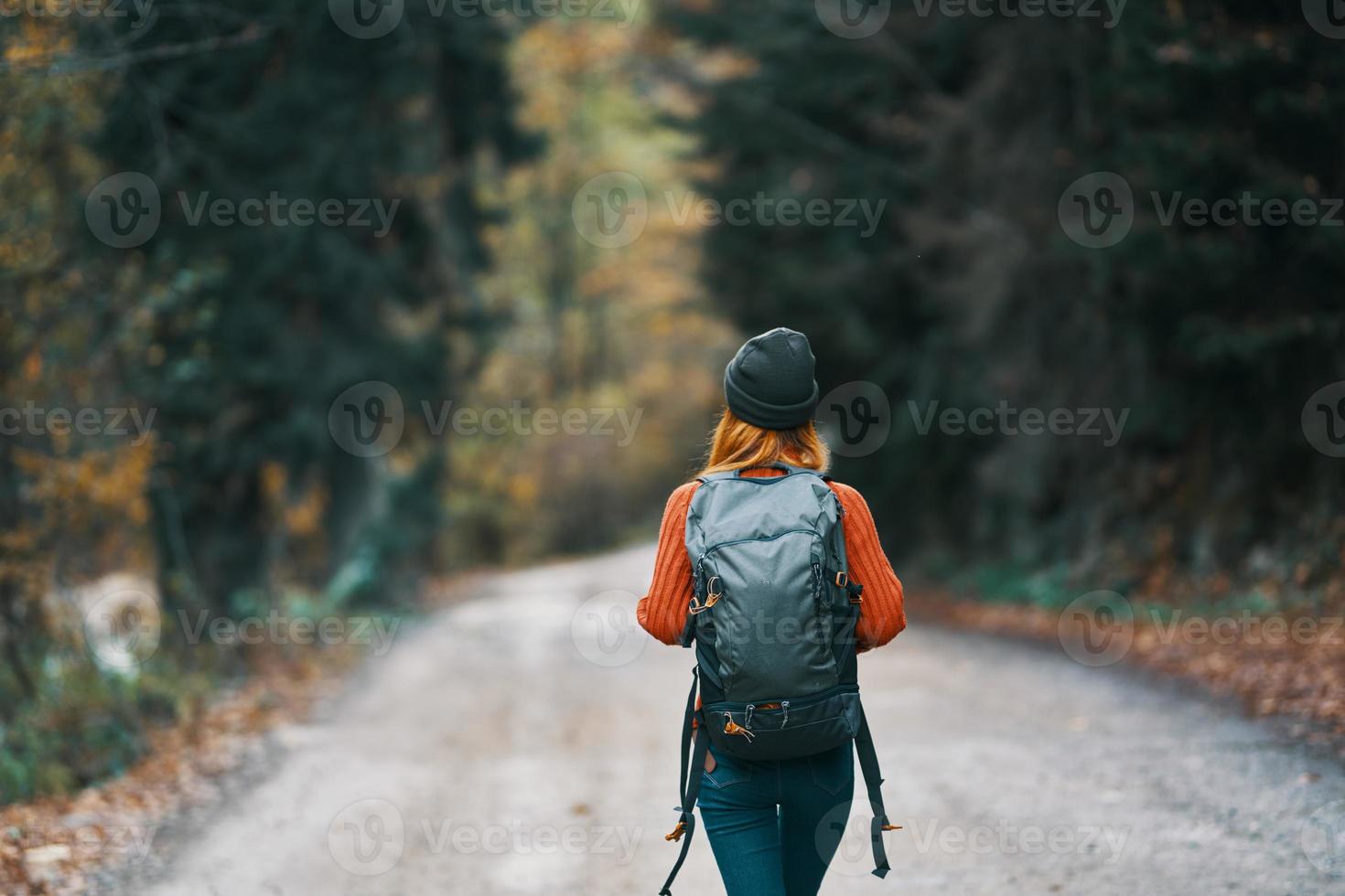 Traveler with a backpack in the forest on the road in autumn trees model photo