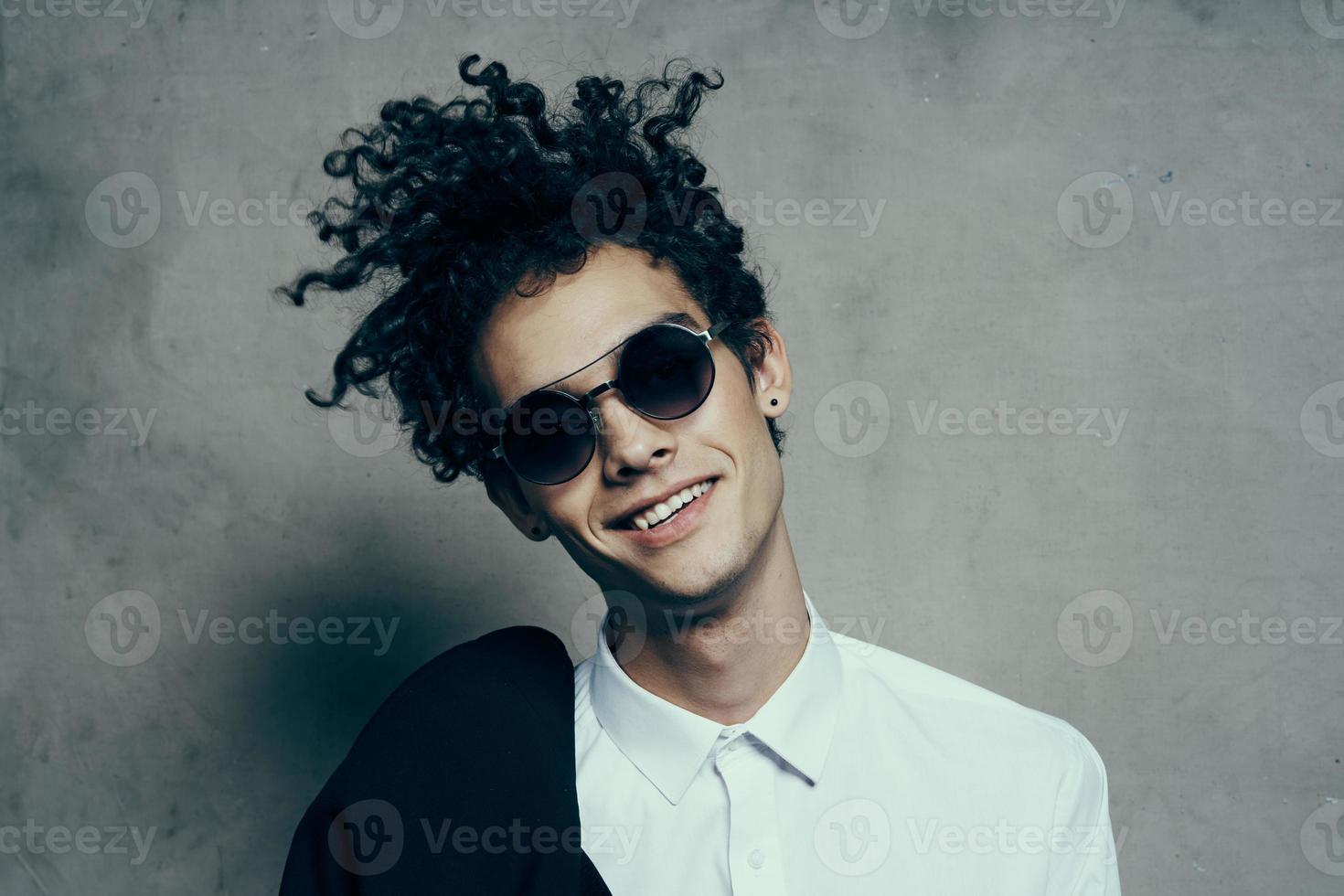 emocional chico con Rizado pelo adolescente clásico traje Gafas de sol camisa modelo foto