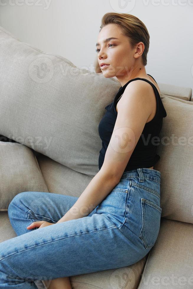Young woman with short haircut hair having fun at home on the couch smile and happiness, vacation at home, natural posing without filters, free copy space photo