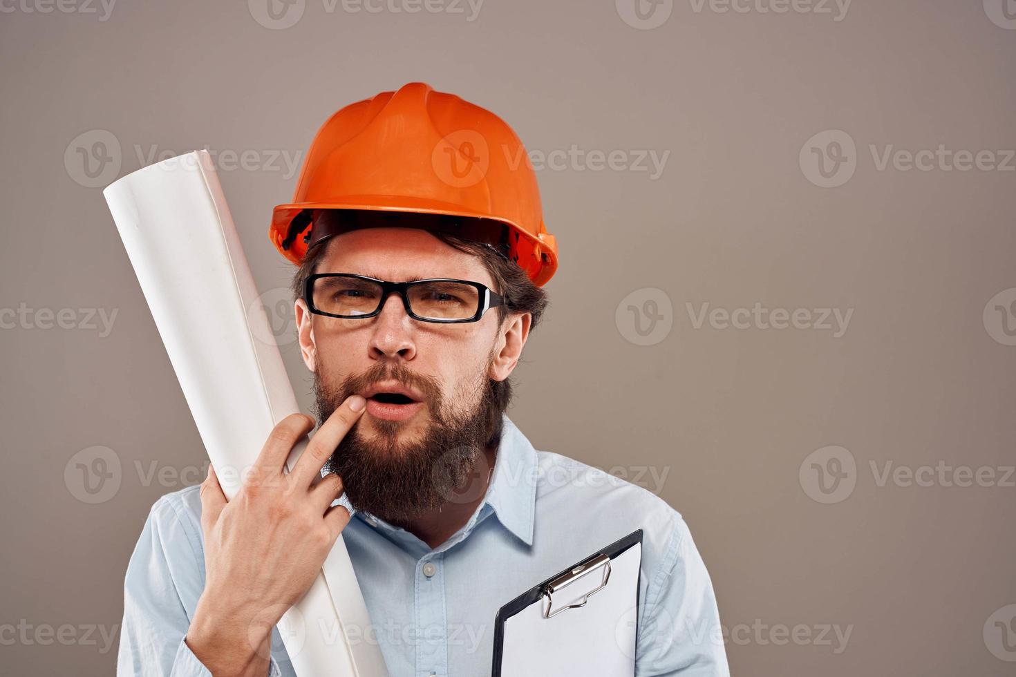 Male engineer with glasses in orange paint. Professional blueprints in hands photo