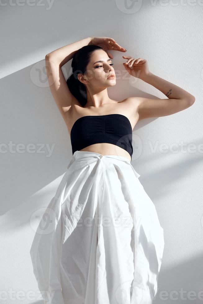 portrait of a woman in fashionable clothes on a light background and a falling shadow photo