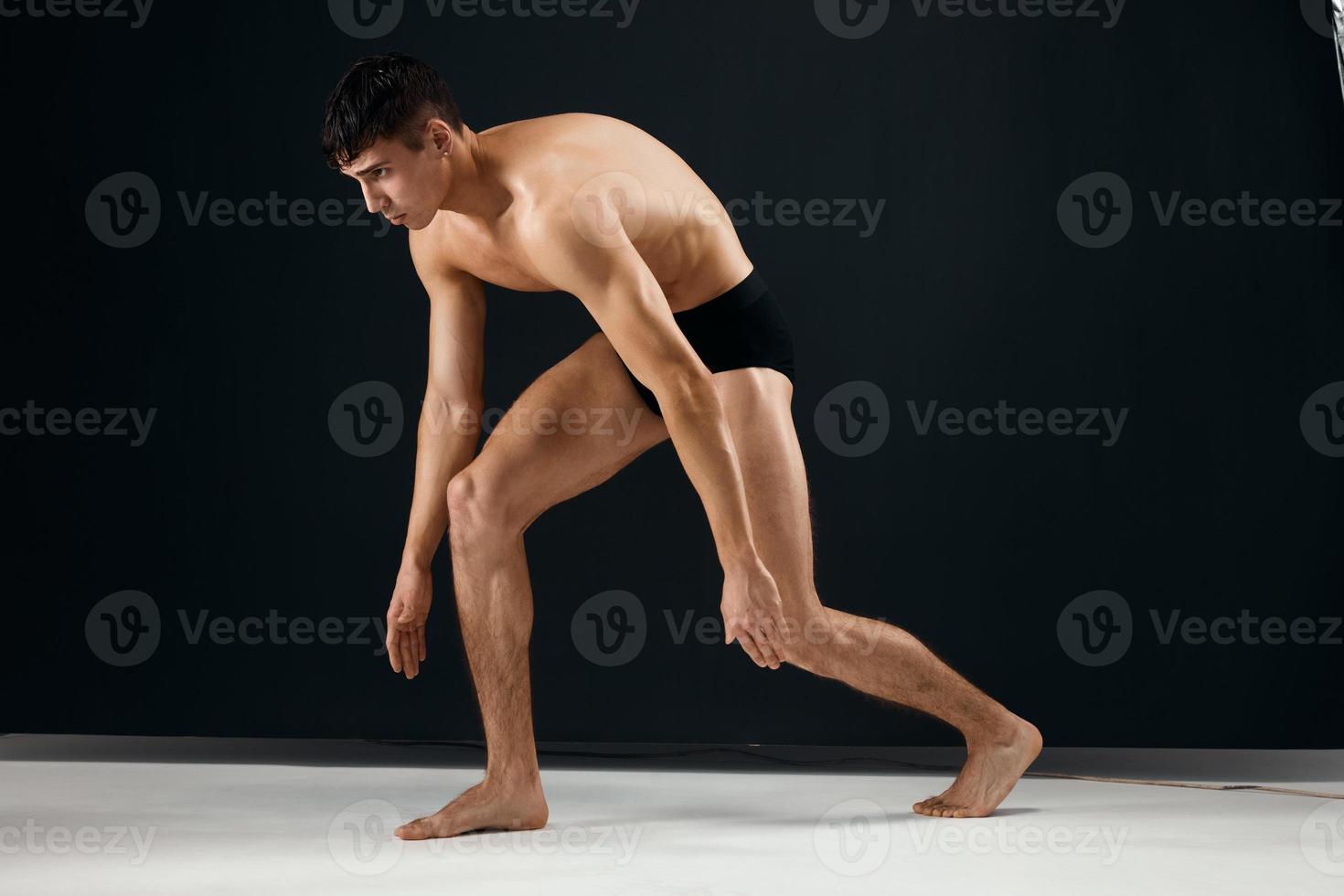 sporty man with pumped up muscular body black panties posing dark studio background photo