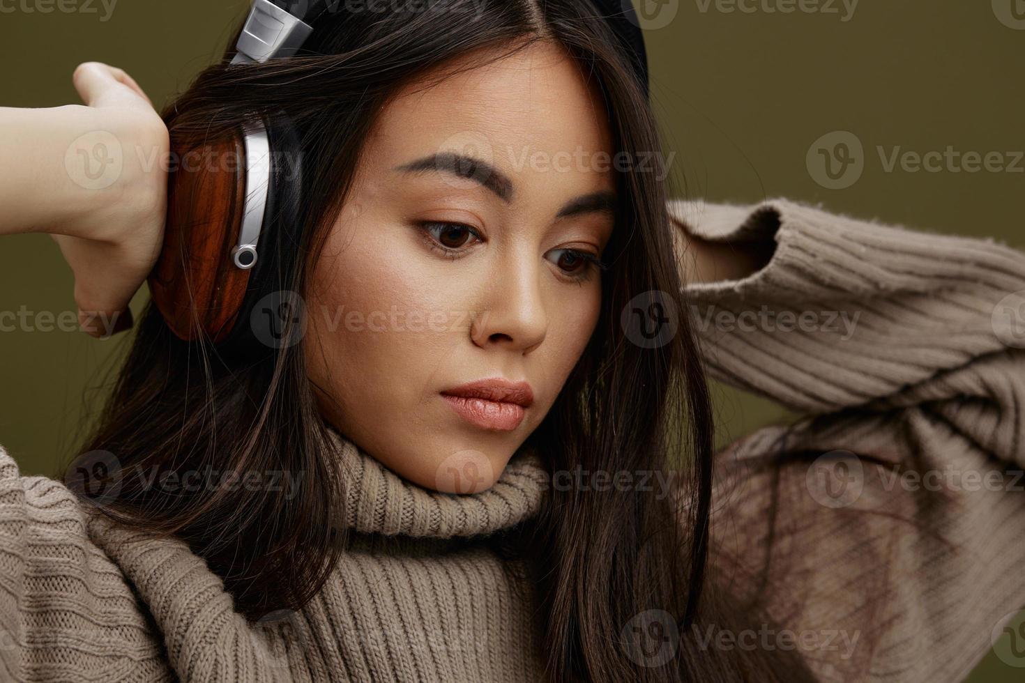 joven mujer en un suéter escuchando a música con auriculares divertido estudio modelo foto