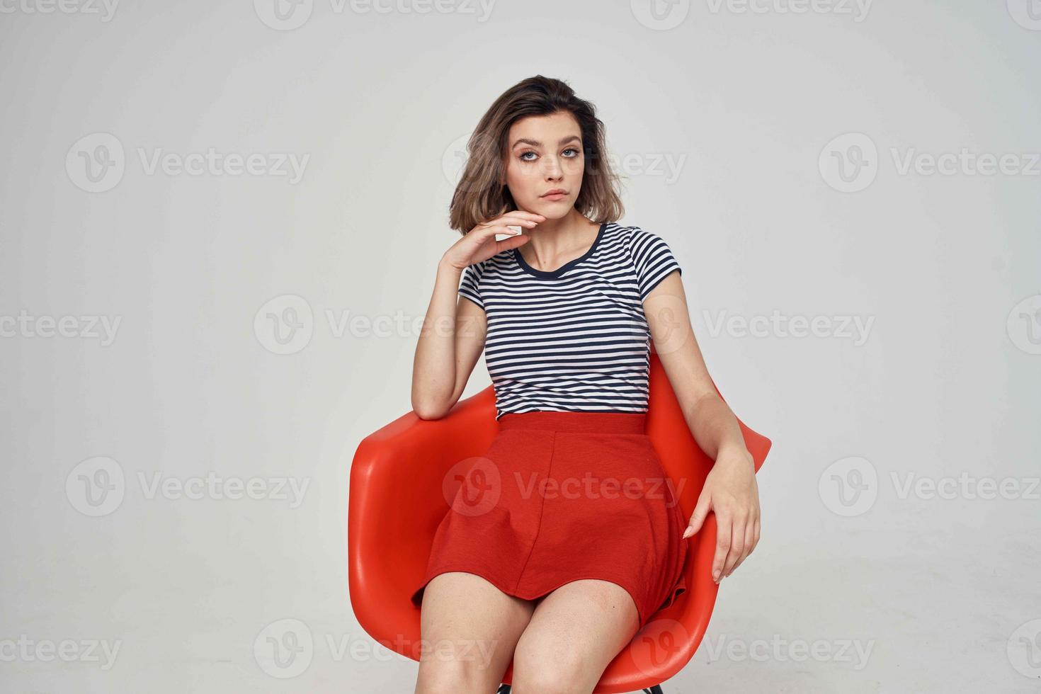 bonito mujer en de moda ropa sentado en el rojo silla foto