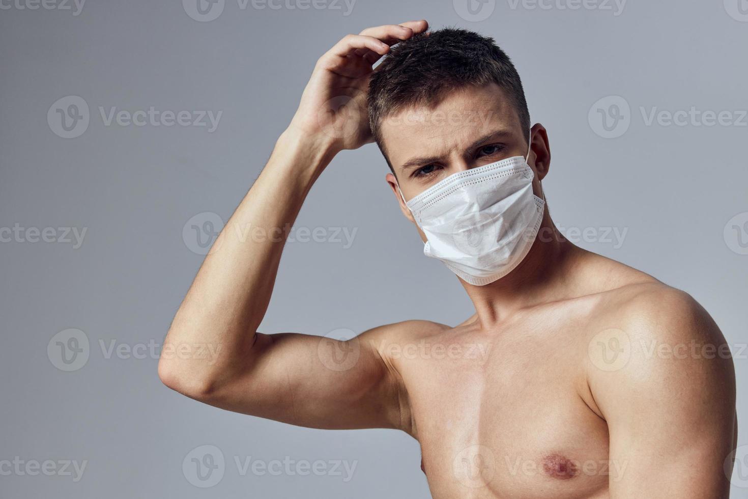 sport guy holding hand on head medical mask muscular body close-up photo