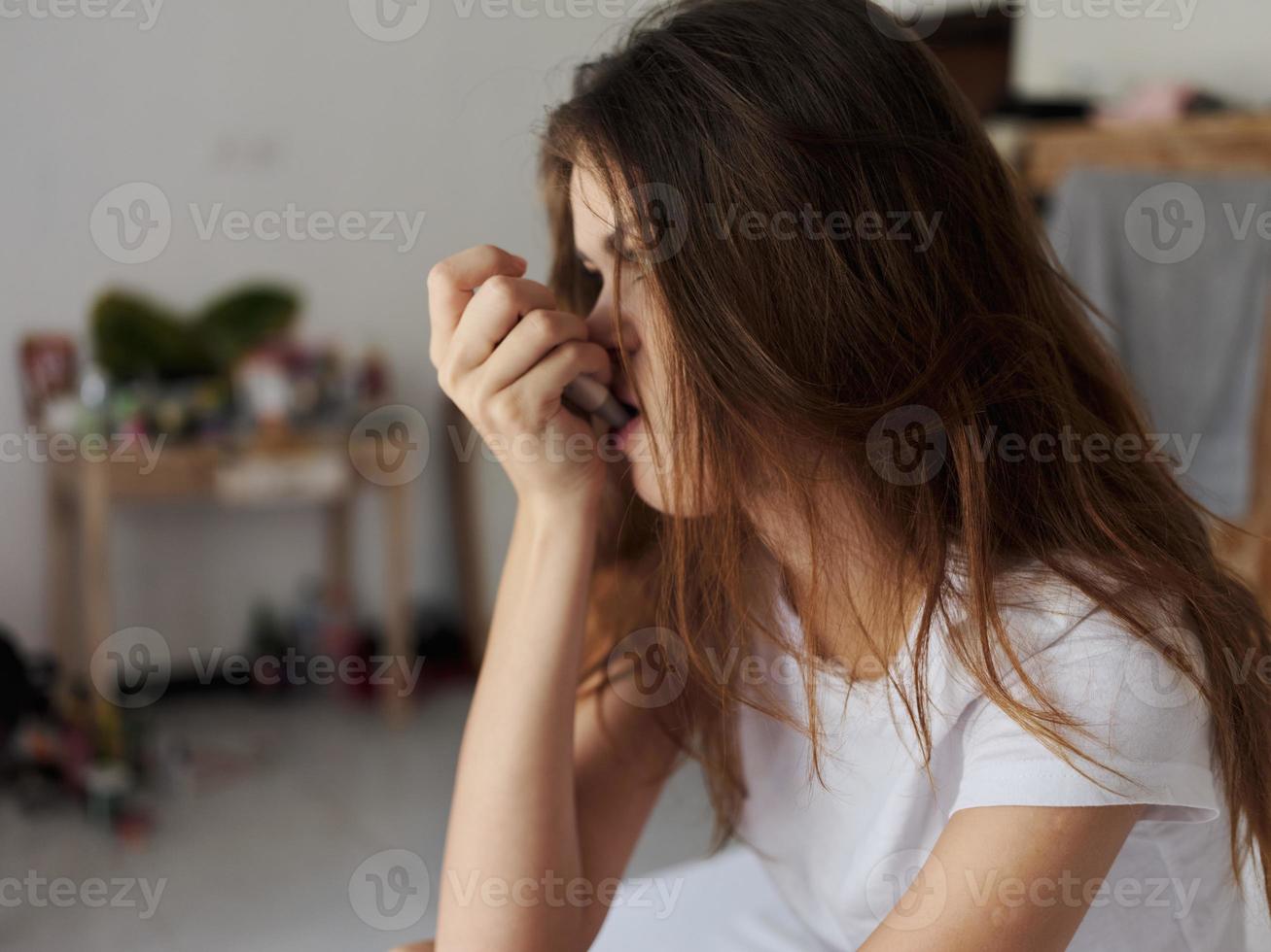 woman sitting in the bedroom with a thermometer in her mouth close-up photo
