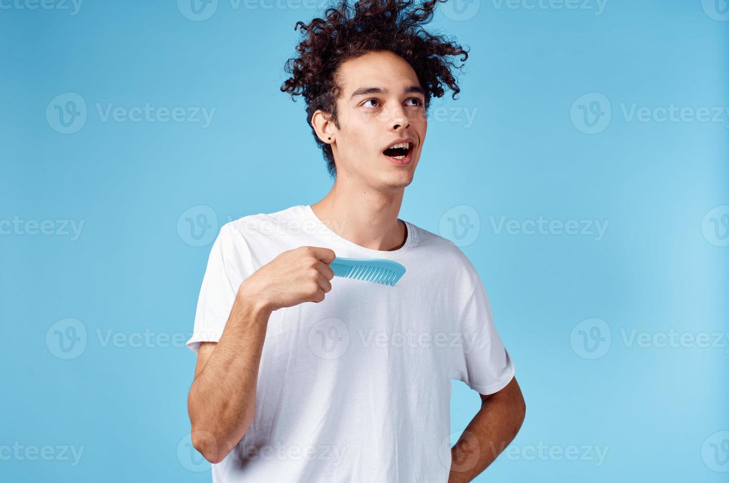 Cheerful guy with curly hair and blue hairbrush isolated background model cropped view photo