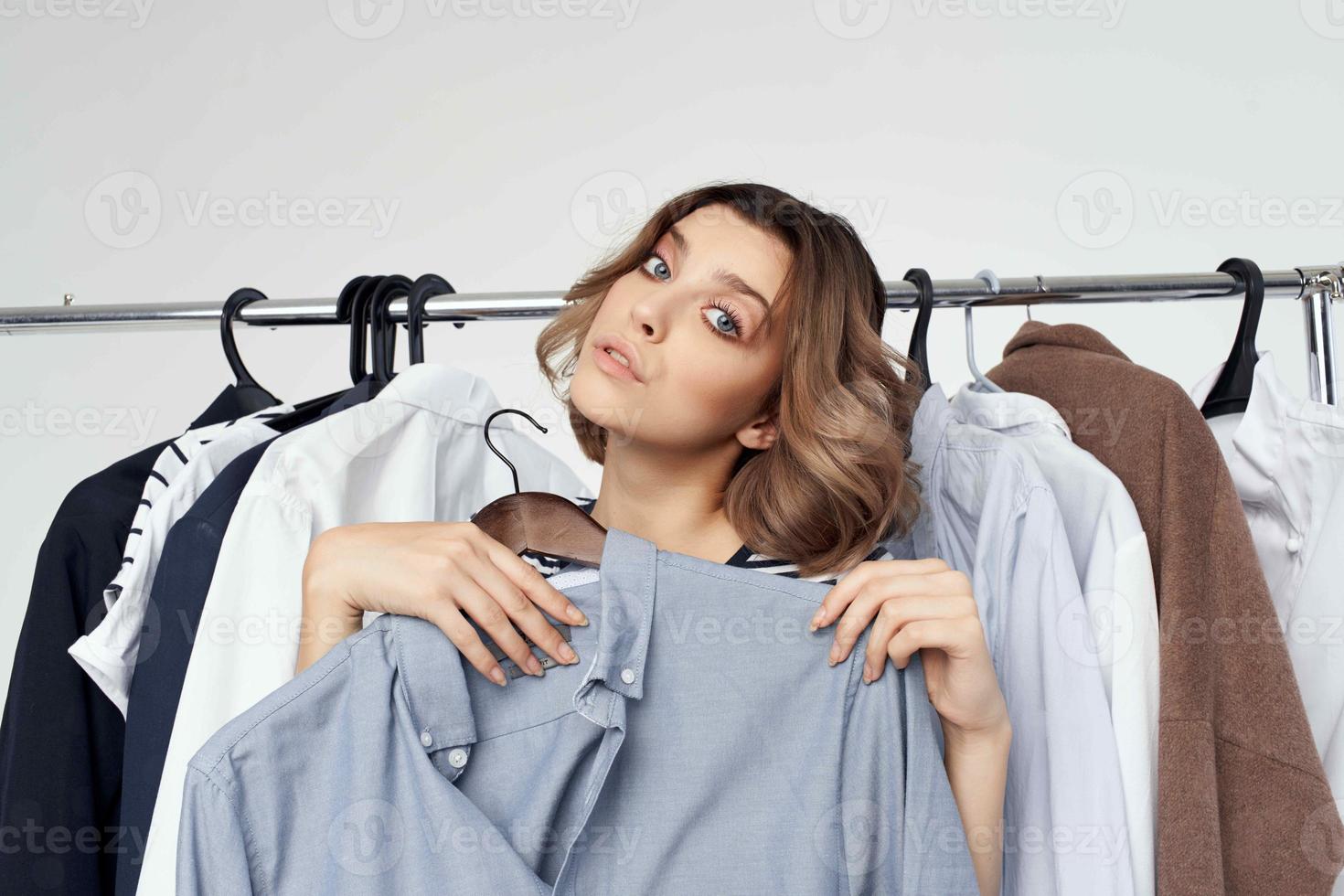 beautiful woman next to clothes fashion fun light background photo