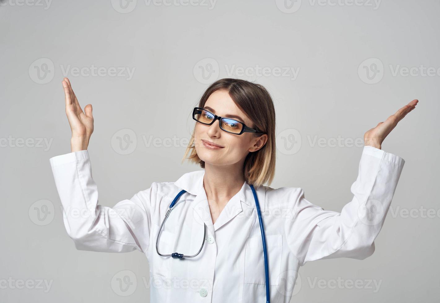 female nurse in a medical gown gesturing with her hands on a light background photo