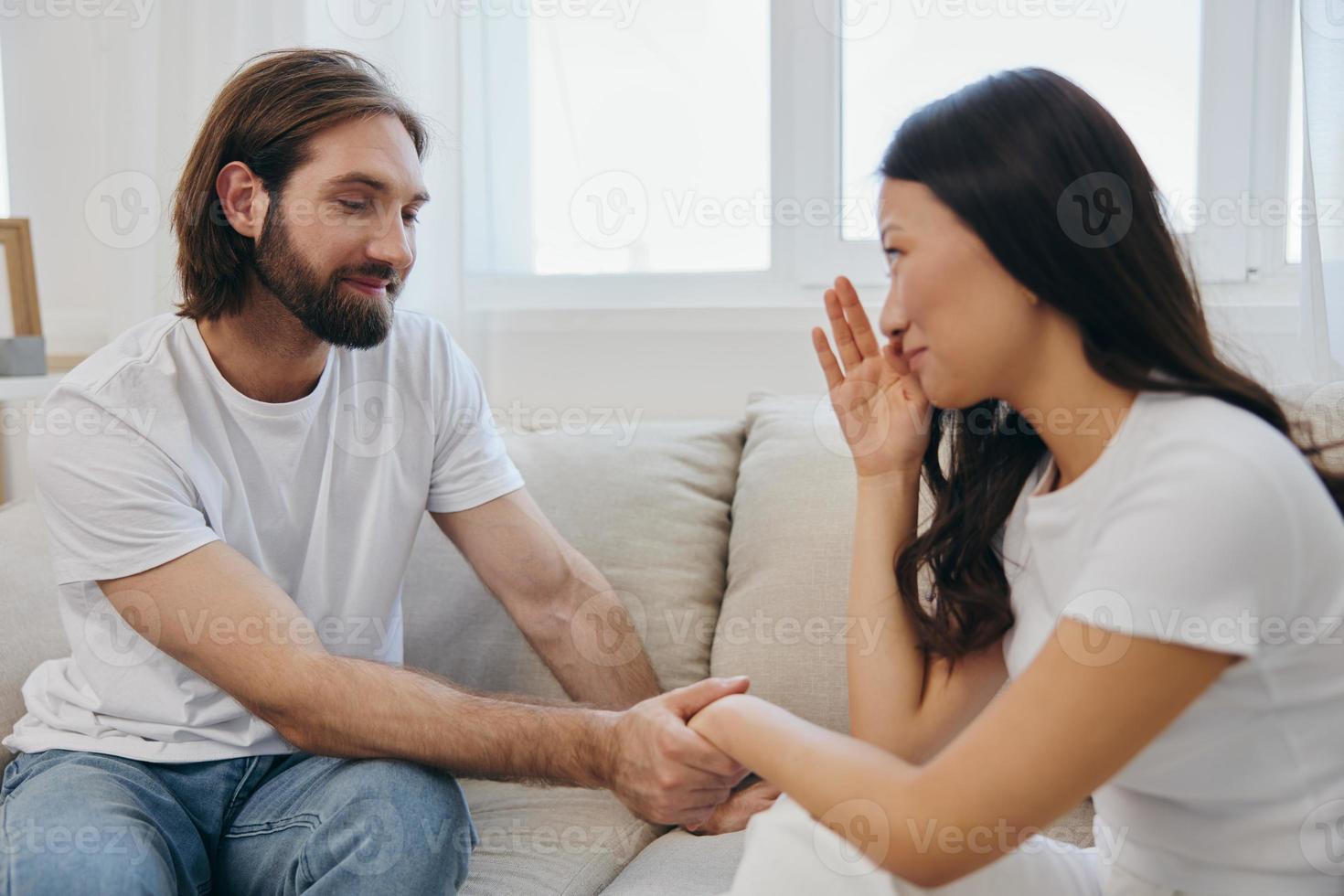 An Asian woman is sad and crying with her male friend at home. Stress and misunderstanding in a relationship between two people and supporting each other's mental and emotional well-being photo