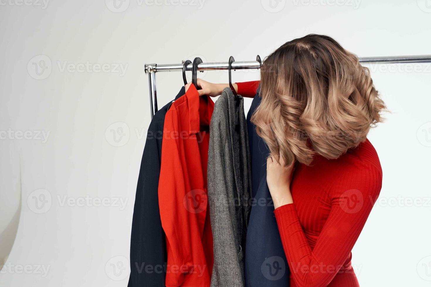 beautiful woman in a red jacket near the wardrobe retail light background photo