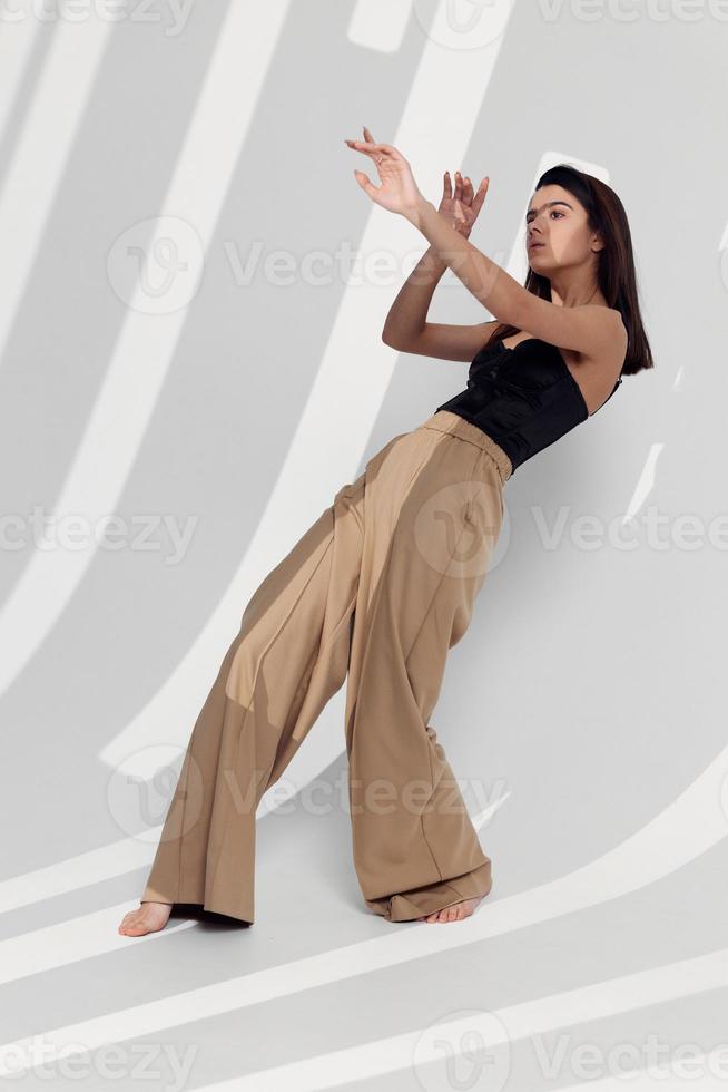 attractive woman in beige pants and black top gestures with her hands photo