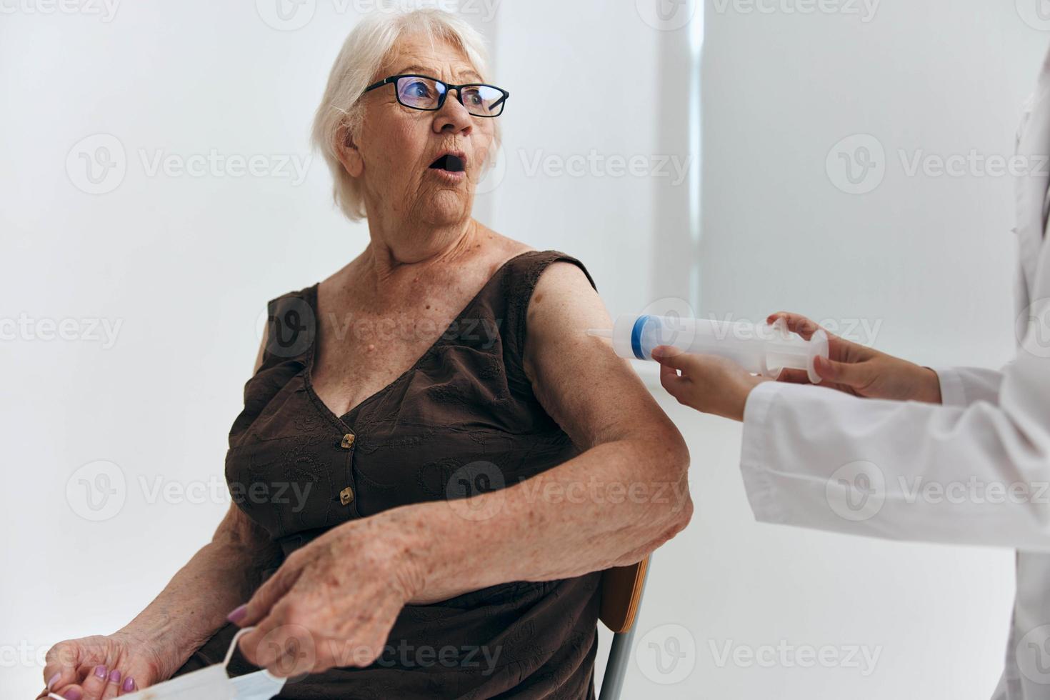 enfermero dando inyección a un mayor mujer con un jeringuilla hospital foto