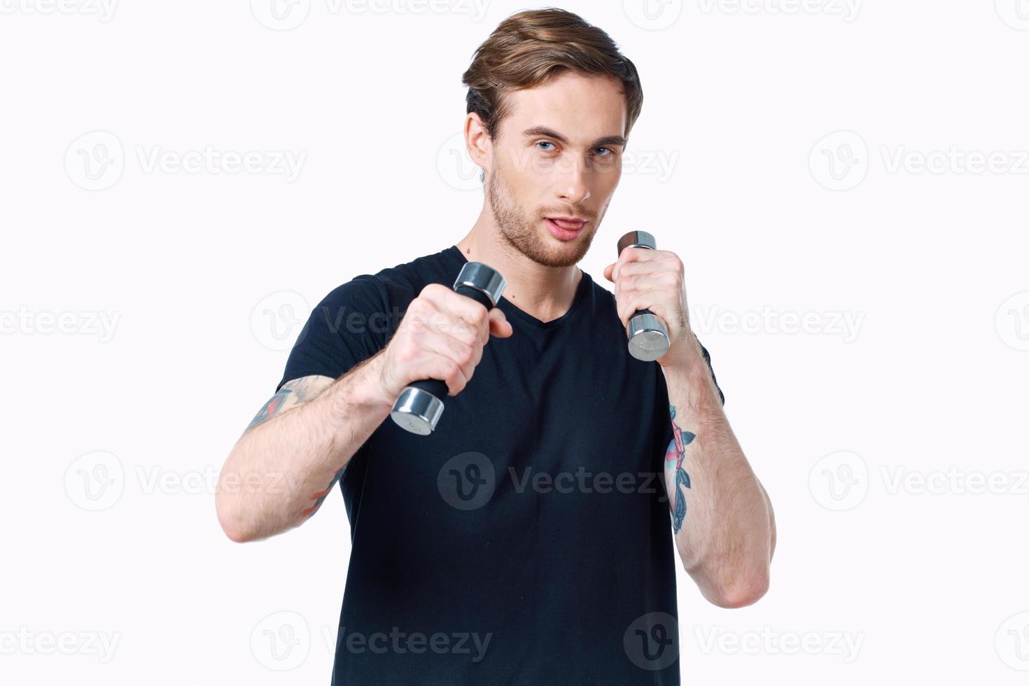 athlete with dumbbells in his hands on a white background in a black t-shirt photo